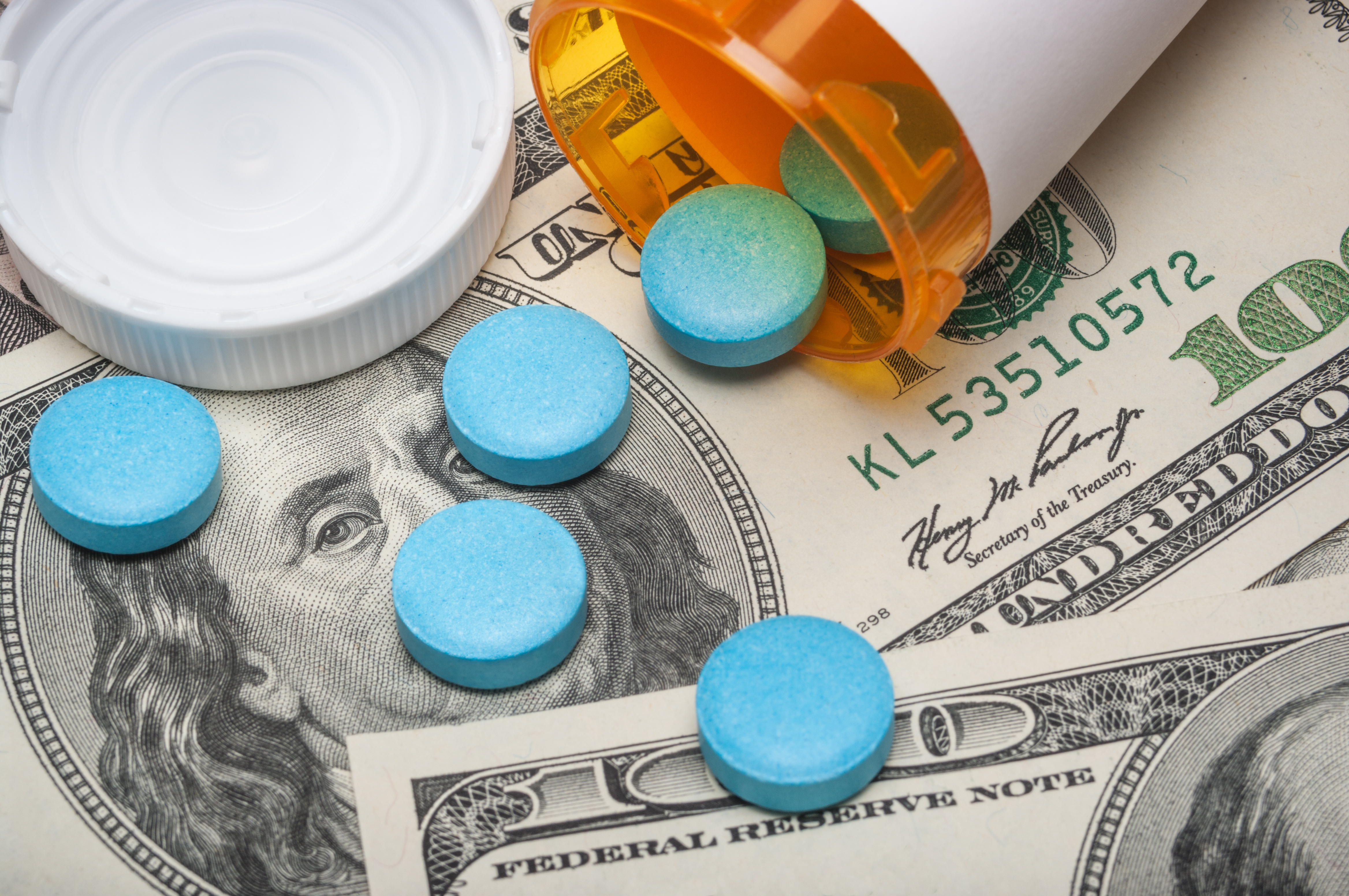 blue pills lying on top of cash