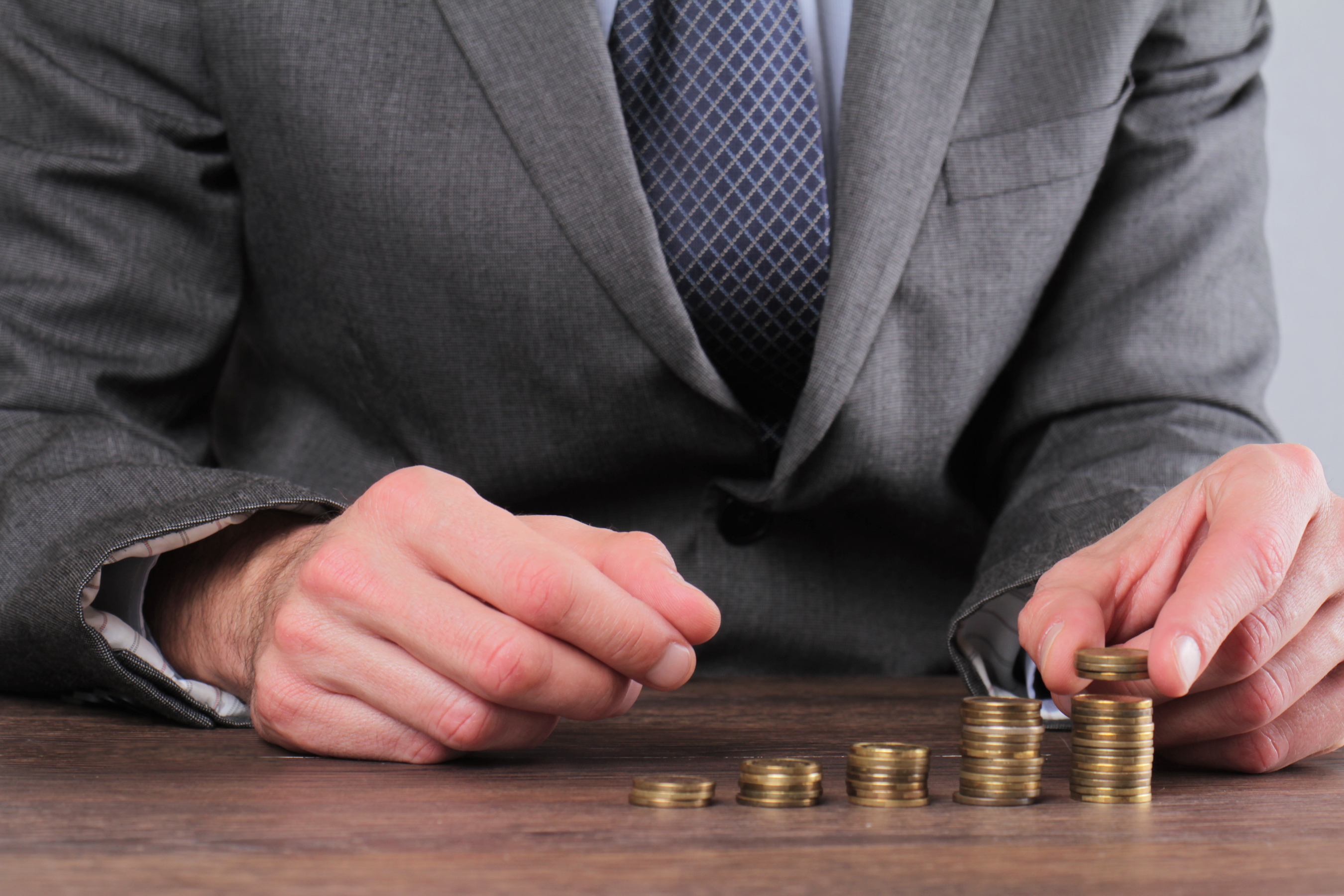 Businessman illustrating compound returns with stacks of change.