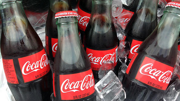 Bottles of Coca-Cola chill in a bucket of ice.