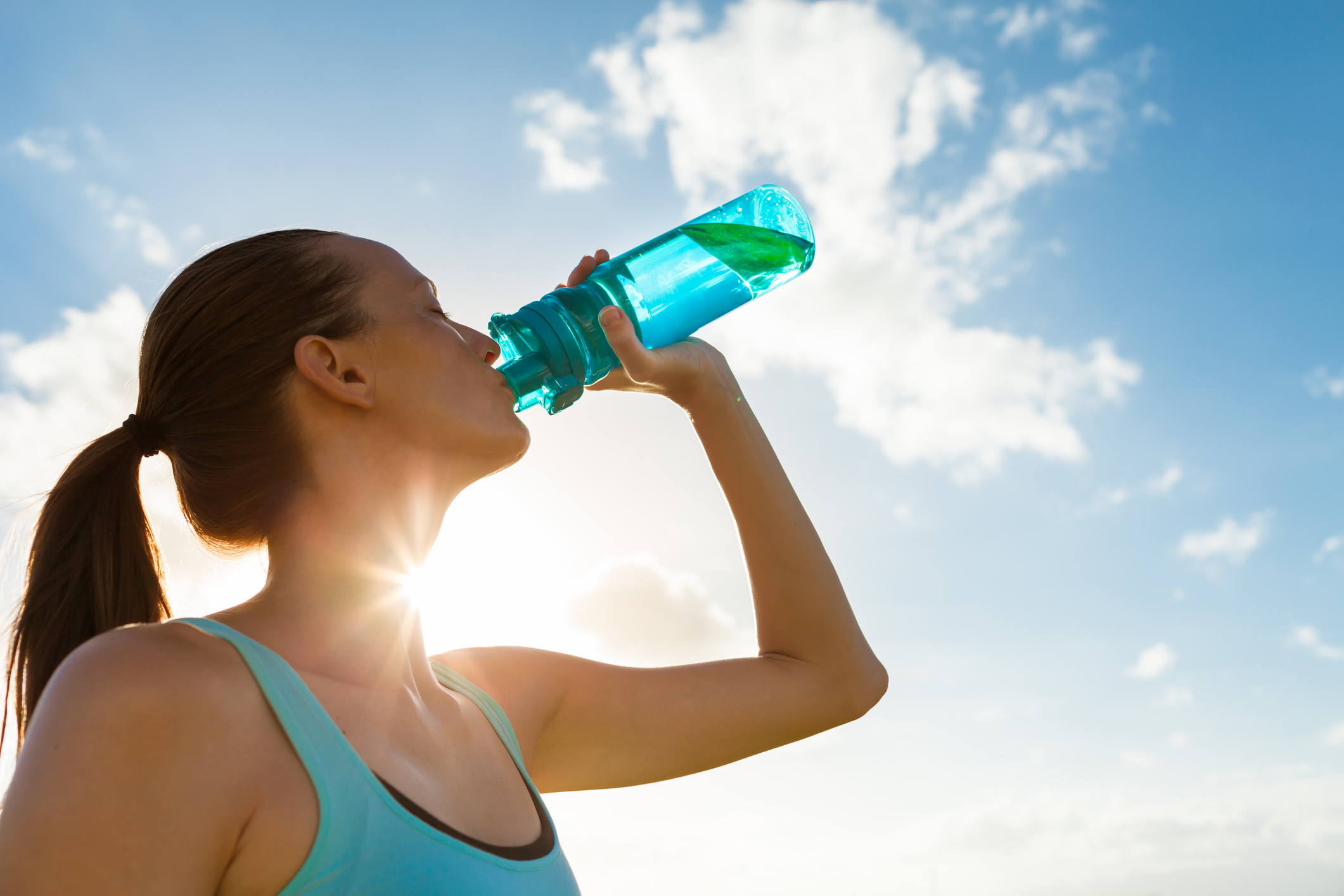A woman in exercise clothing drinks from her water bottle.