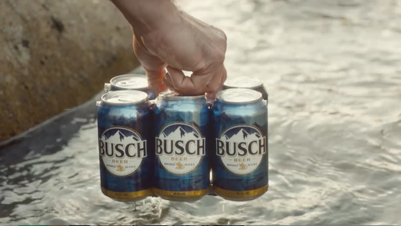 A man carrying a six-pack of Busch beer.
