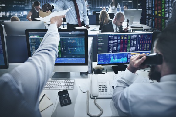 Image of traders using computer screens on a stock trading floor