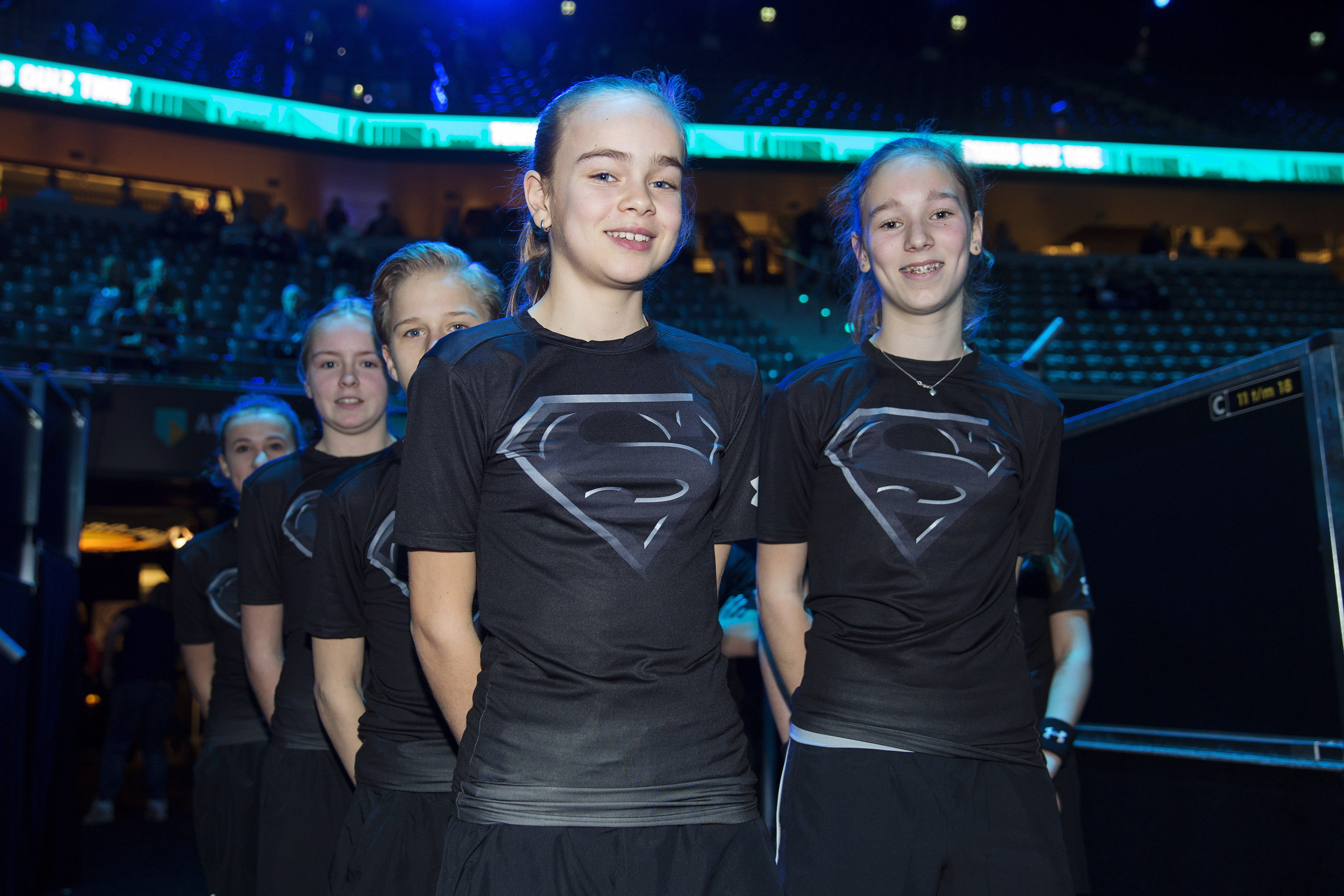 Ballkids at tennis tournament in batman versus superman themed Under Armour t-shirts.