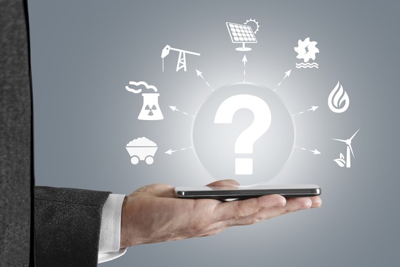 A man's hand holds a phone, out of which pop symbols of energy production, with a question mark in the middle.