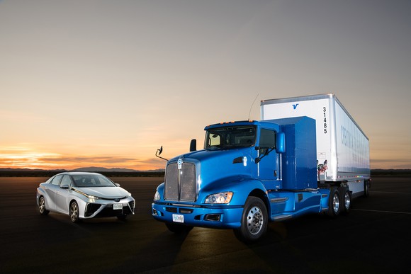 A white Toyota Mirai sedan next to the electric truck.