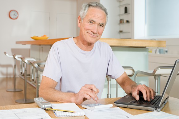 A senior man calculating his Social Security benefit and examining his finances.