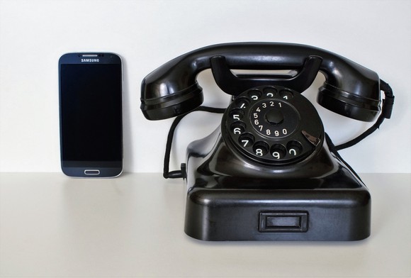 A rotary phone next to a modern smartphone.