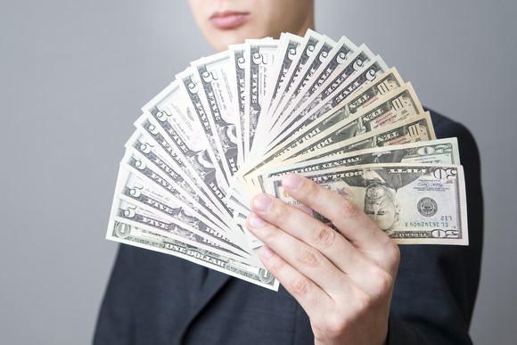An investor fanning his dividend income in front of his face.