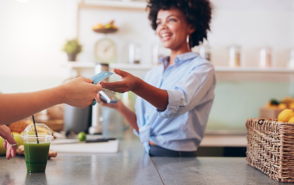 A person handing a credit card to a merchant.