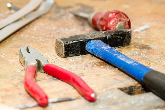 A hammer, screwdriver, and pliers on a workbench.