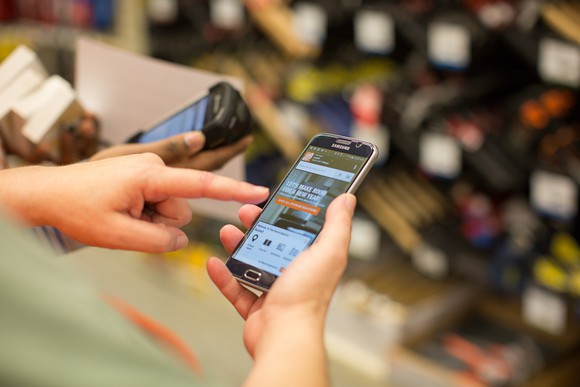 Hands holding mobile phone using The Home Depot app.