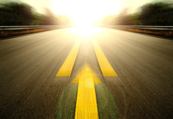 A road with signs pointing toward the sun