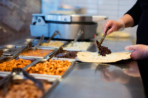 worker puts black beans on a tortilla
