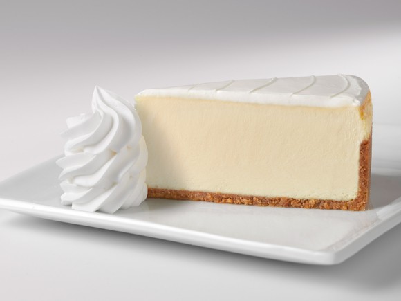 The original recipe-style cheesecake, served with a side of whipped cream on a white plate.