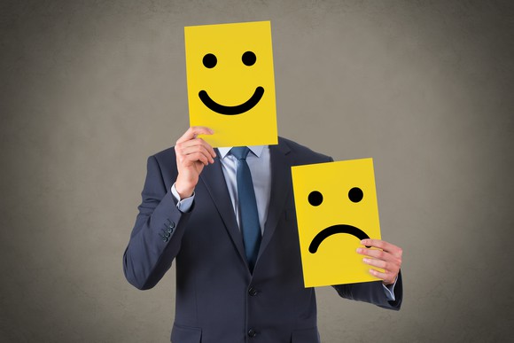 A person holding up a smiley face.