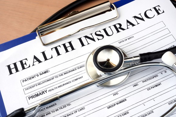 A stethoscope laying on a health insurance enrollment form.