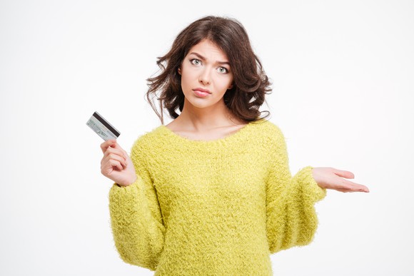 A confused young adult with a credit card in her hand.