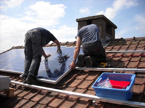 Workers installing solar panels on a residential roof.