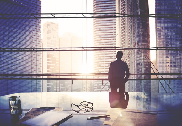 Silhouette of CEO looking through window at city