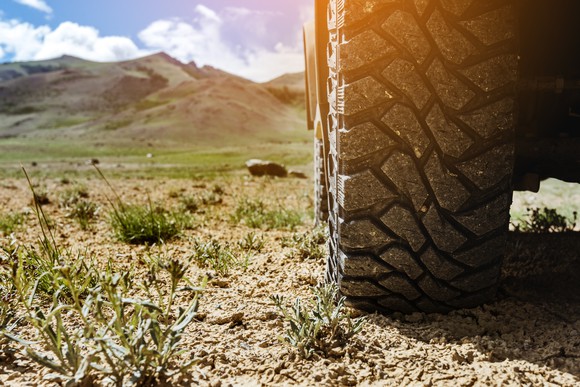 Truck tire in foreground of dirt road