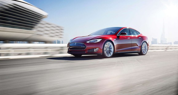 A red Tesla Model S on the road.