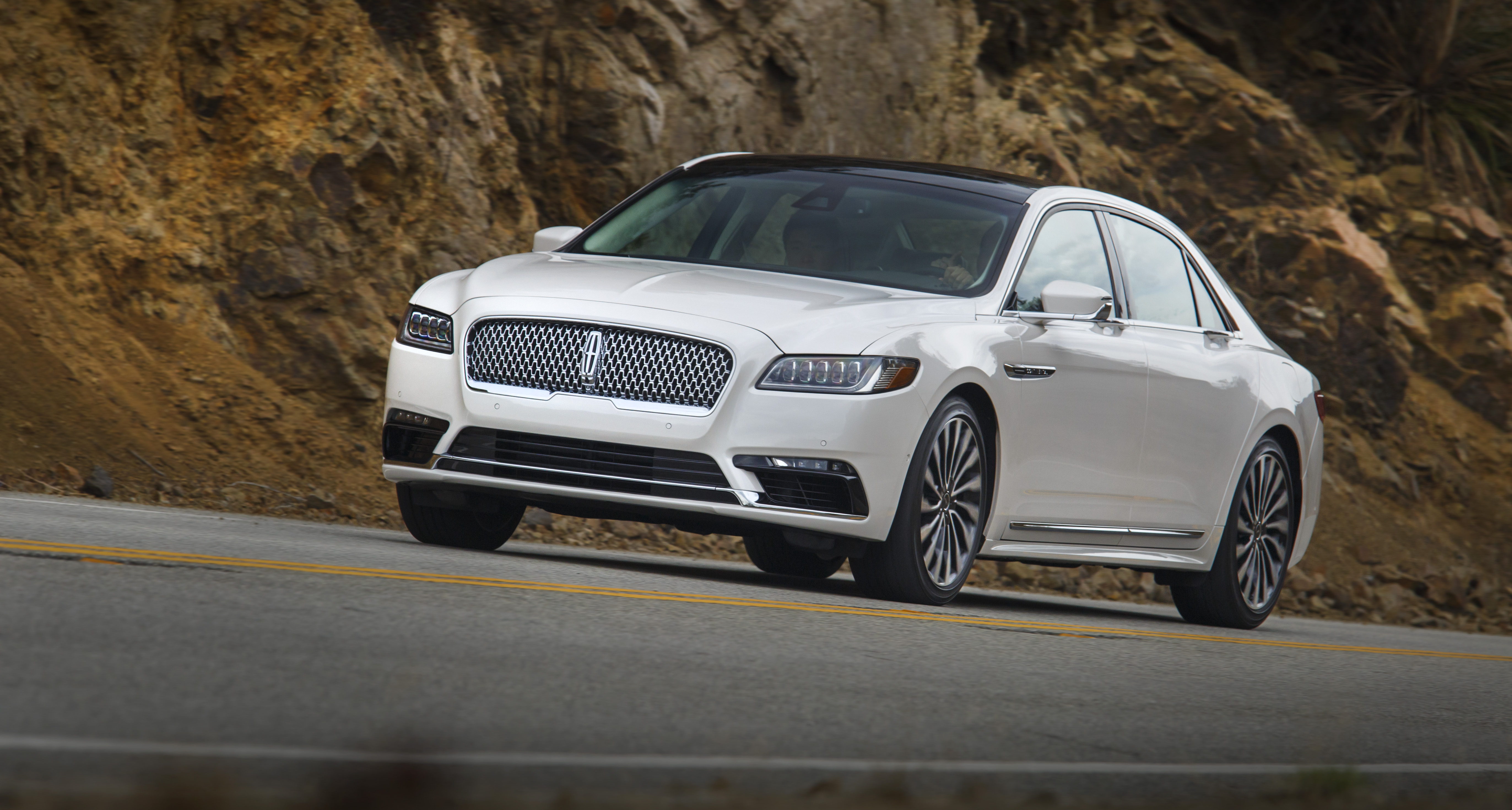 A while Lincoln Continental sedan on a country road.