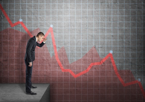 A businessman looking down a stock chart showing losses.