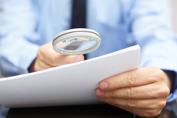 Businessman looking at document through magnifying glass
