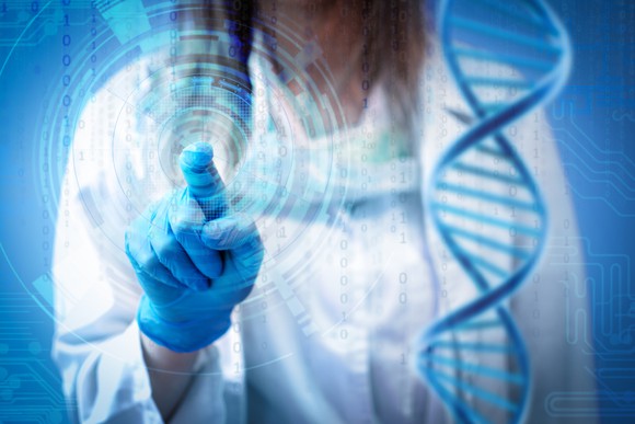 A doctor standing next to a graphic of DNA