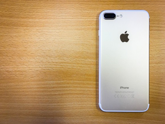The back of an iPhone 7, sitting on a wooden surface.