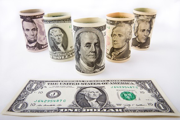 Rolled denominations of money on a table.