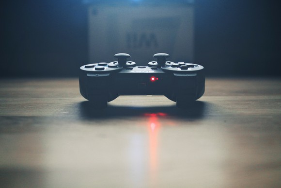 Sony video game console controller lying on a table with red power light turned on.