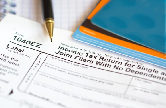 A 1040EZ tax form, with a pen and other items.