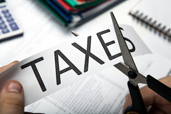Cutting through a piece of paper with the word "taxes" written on it with scissors.