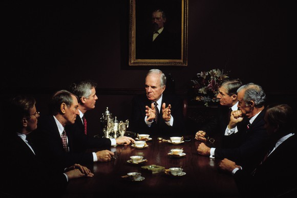 Executives sit around a conference table in board meeting