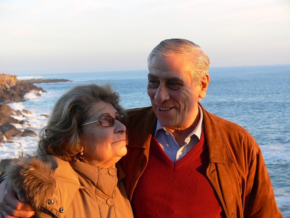 An elderly married couple smiling at one another.