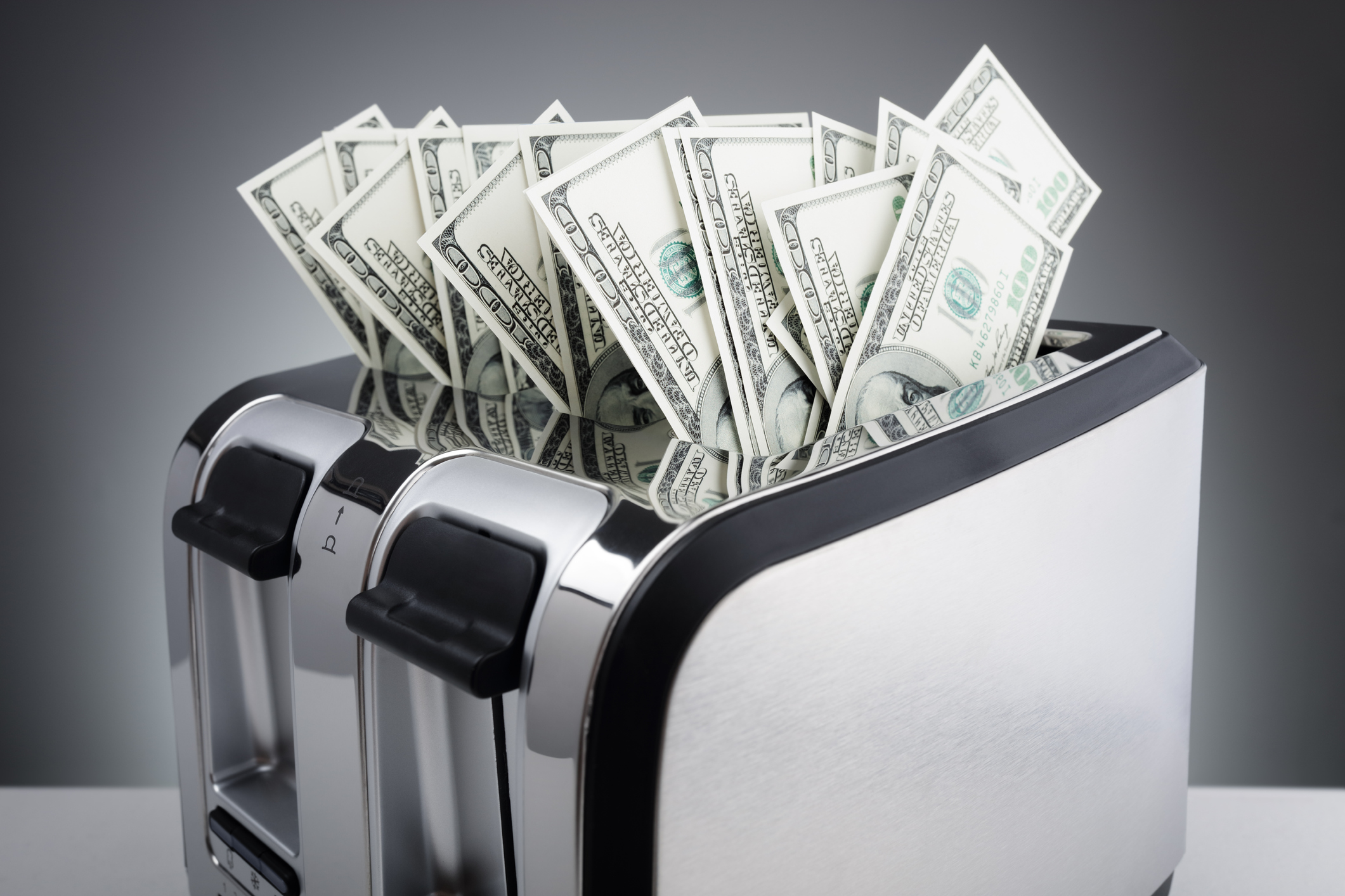 Piles of cash being stuck in a toaster.