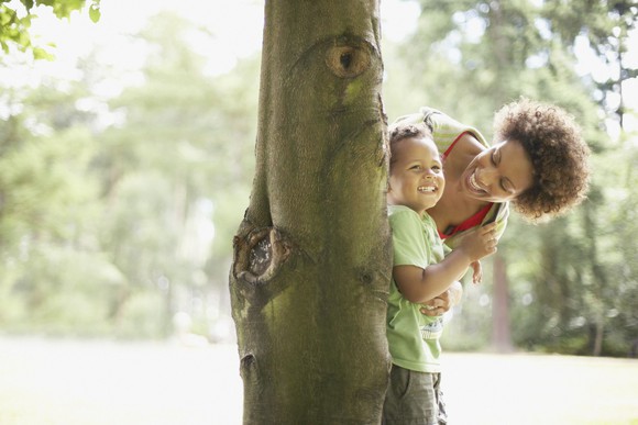 Mother playing hide in seek with son in park