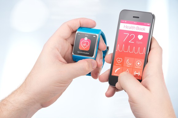 A person checks health readings on an Apple Watch and a smartphone.