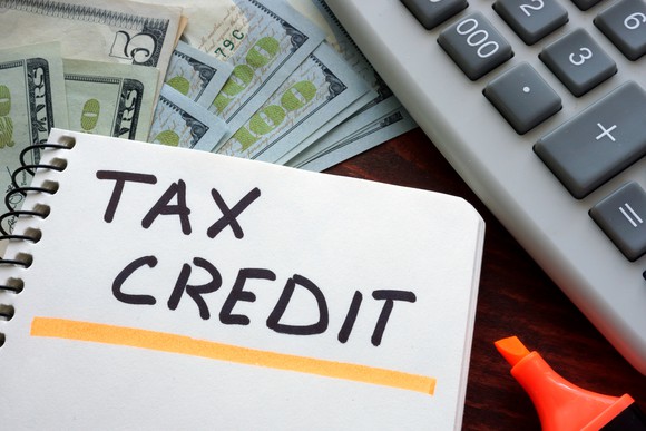 Words "tax credit" written and underlined, next to calculator, money, and highlighter