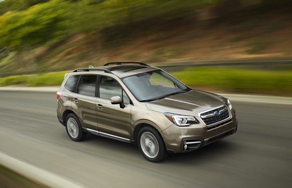 A gold Forester SUV on a hilly road