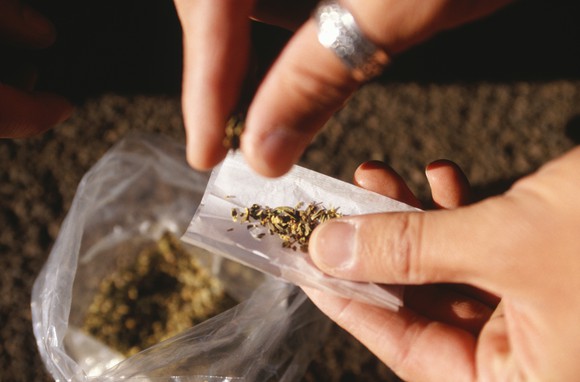 A person rolls a joint from a ziplock bag containing marijuana.