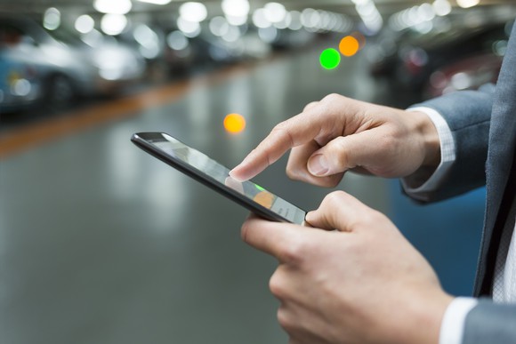 Close-up of a man's hands using a cell phone in a parking lot.