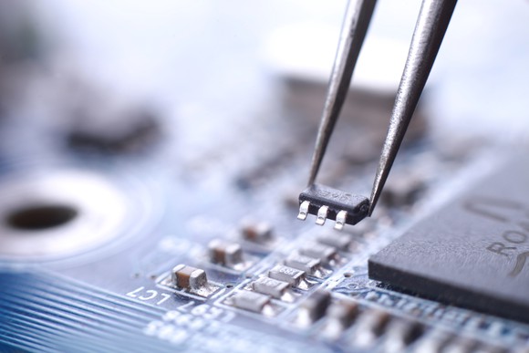 A microchip being placed on a motherboard with tweezers.