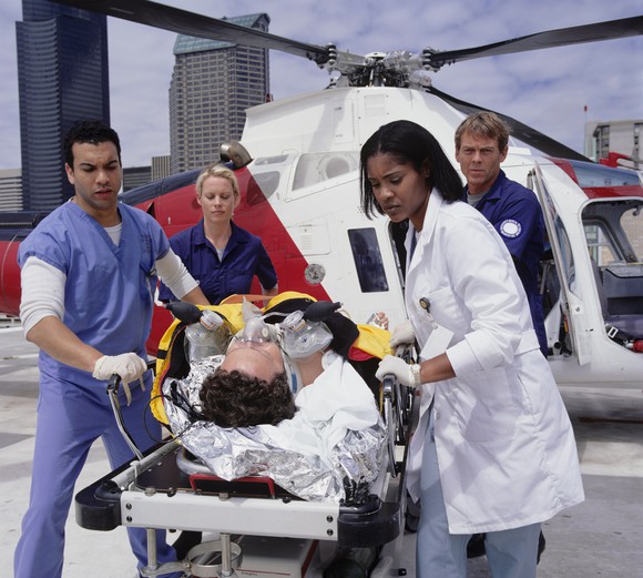 Emergency medial personnel assist moving a patient from a medical helicopter transport.