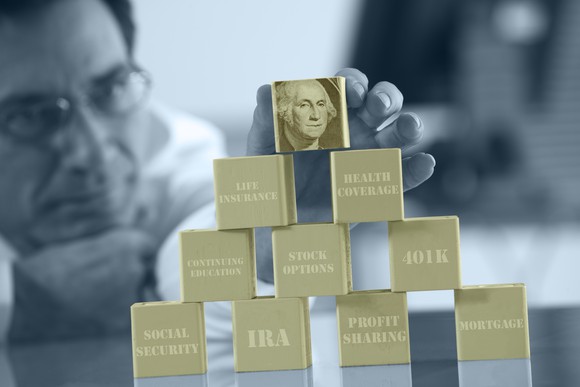 A man stacks gold-colored blocks that represent financial building blocks.