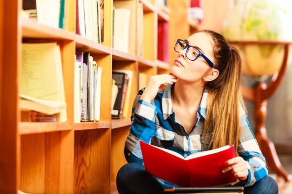 A high school student in a library debating what college she should attend.