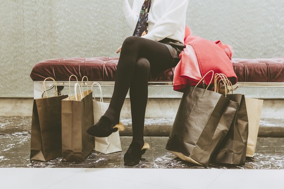 Shopping bags piled at a woman's feet.