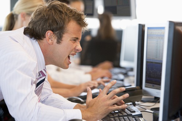A frustrated stock investor yelling at his computer.
