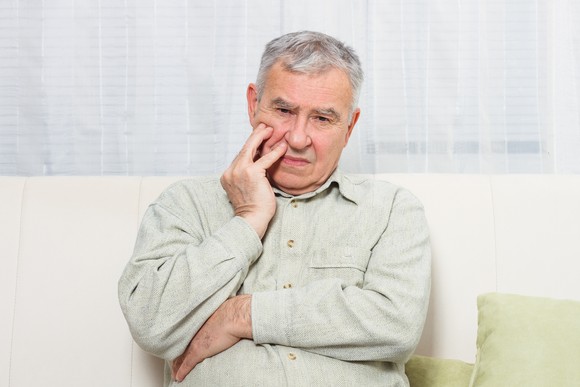 A older man sitting and looking worried.
